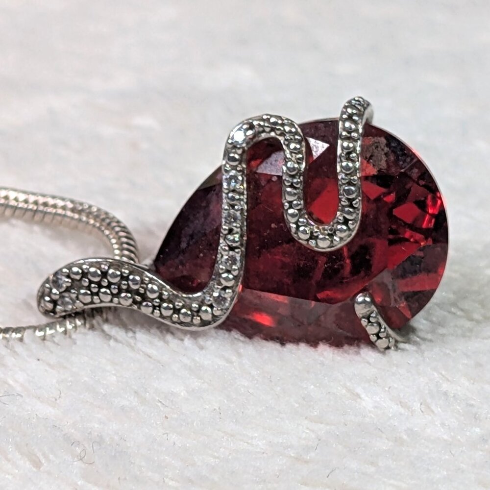 Sterling Silver Pendant of a Snake holding a Red Crystal.